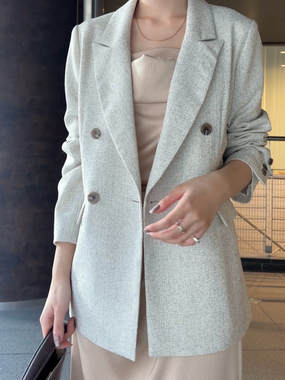 ホワイト系のテーラードジャケット、ブラウン系のハンドバッグ、ブラウン系のブーツを着用したレディースの冬コーディネートの4枚目の写真