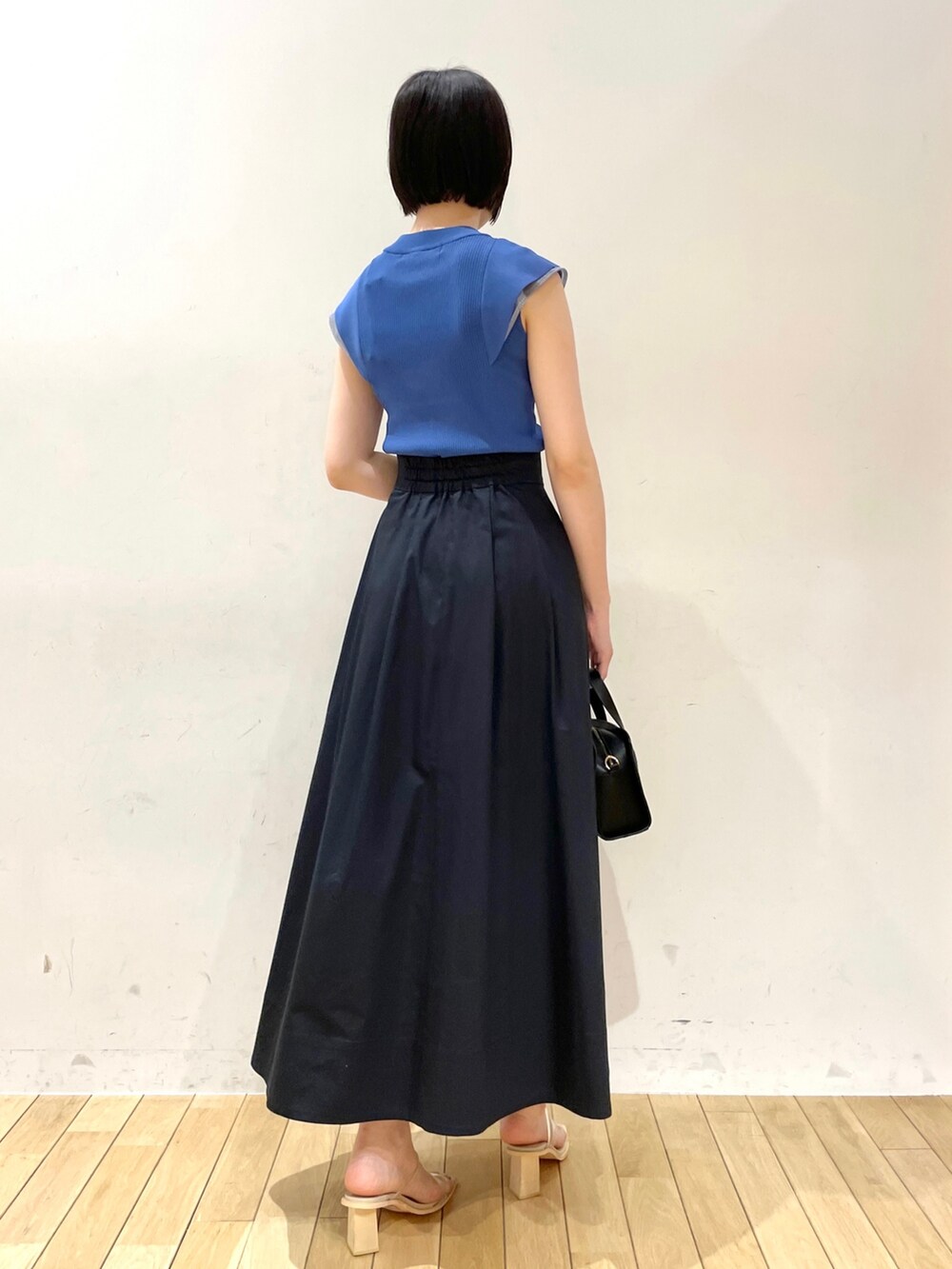 ブルー系のスカート、ブルー系のニット/セーター、ブラック系のショルダーバッグを着用したレディースの夏コーディネートの4枚目の写真