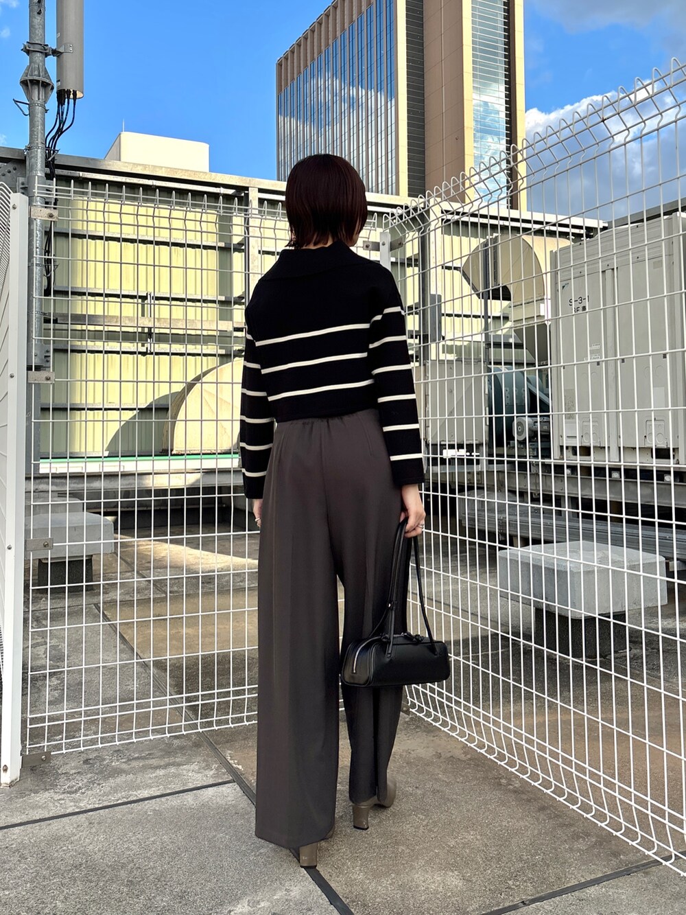 グレー系のその他パンツ、ブラック系のニット/セーター、グレー系のムートンコートを着用したレディースの冬コーディネートの3枚目の写真