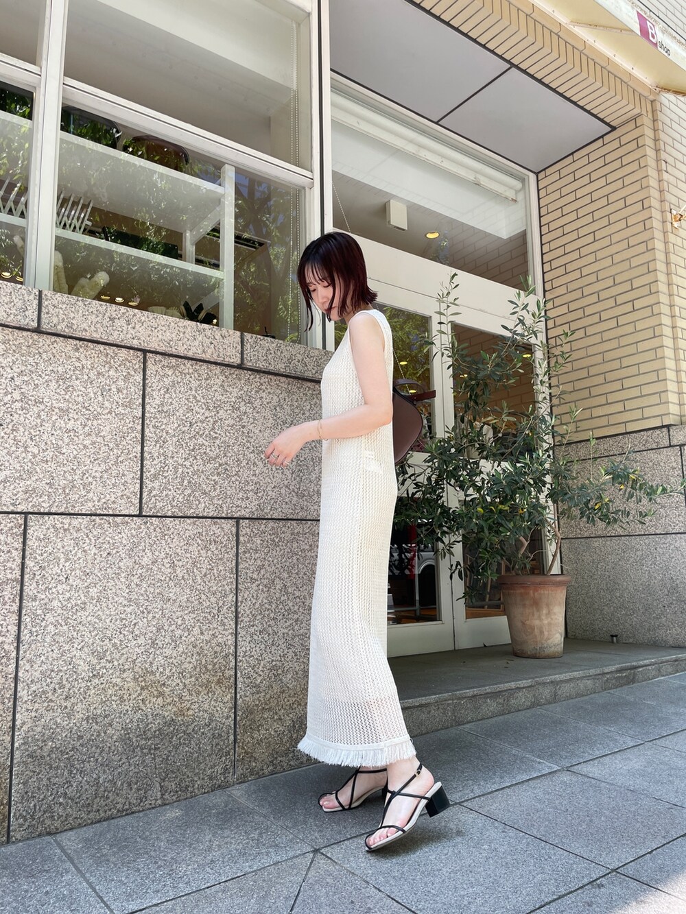 ブラック系のサンダル、ホワイト系のワンピース、ブラウン系のショルダーバッグを着用したレディースの夏コーディネートの3枚目の写真