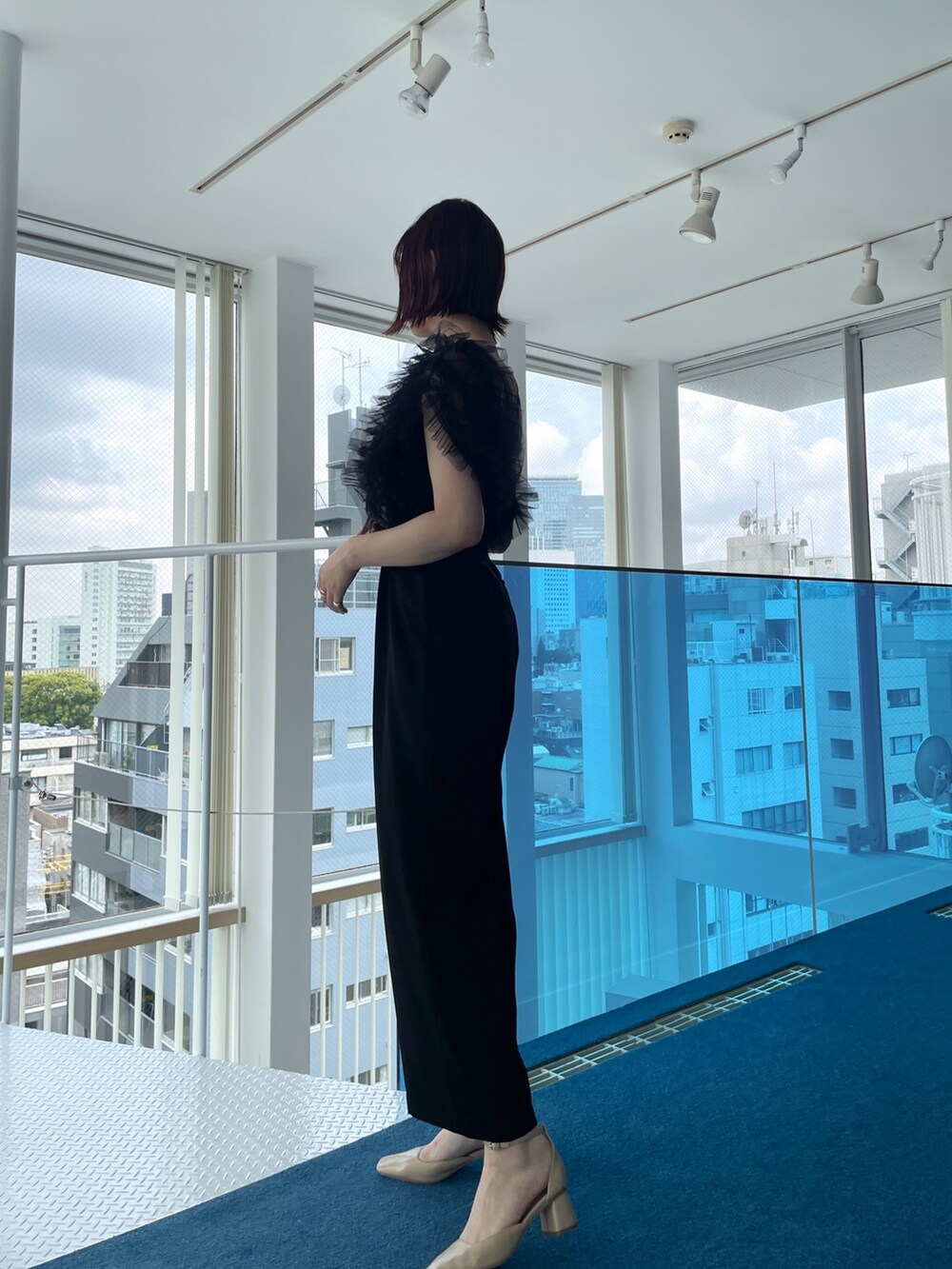 ブラック系のパンツドレス、ベージュ系のパンプスを着用したレディースの春コーディネートの3枚目の写真