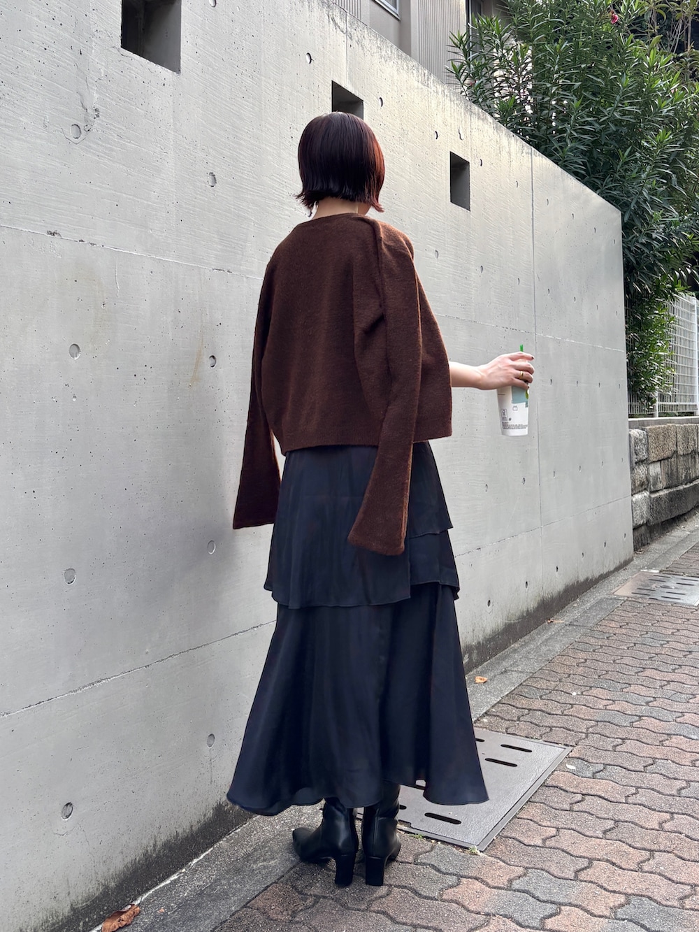 ブラック系のスカート、ブラウン系のアンサンブル、ブラック系のブーツを着用したレディースの秋コーディネートの4枚目の写真