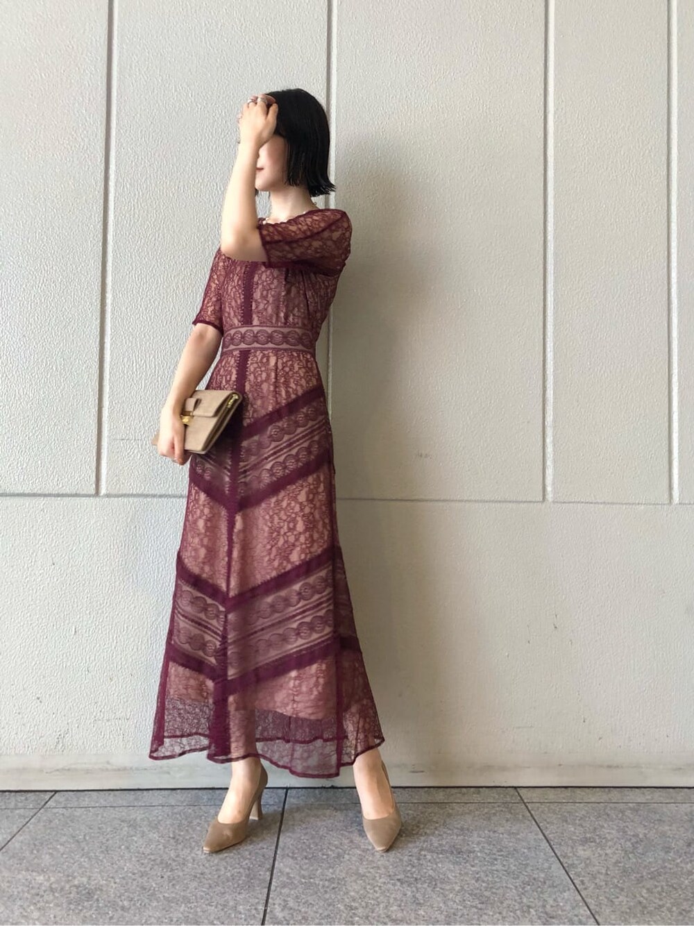 レッド系のドレス、ベージュ系のパンプス、ベージュ系のクラッチバッグを着用したレディースの秋コーディネートの2枚目の写真