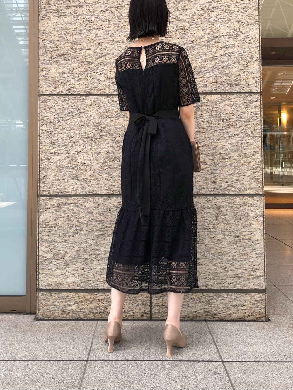 ベージュ系のパンプス、ベージュ系のクラッチバッグ、ブラック系のドレスを着用したレディースの秋コーディネートの4枚目の写真