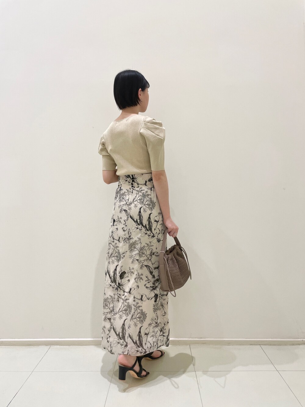 ホワイト系のスカート、ベージュ系のニット/セーター、ブラウン系のハンドバッグを着用したレディースの春コーディネートの4枚目の写真