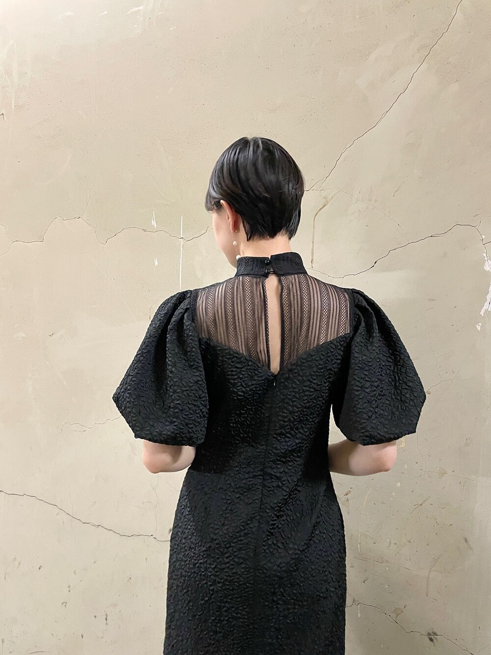 ブラック系のドレス、ゴールド系のハンドバッグ、ゴールド系のパンプスを着用したレディースの秋コーディネートの7枚目の写真