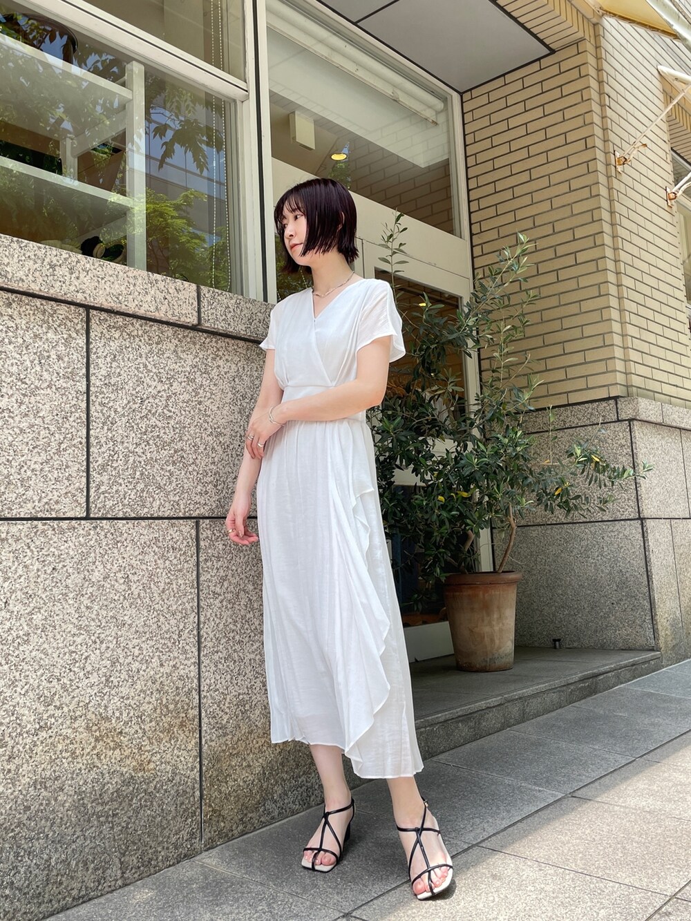 ブラウン系のショルダーバッグ、ホワイト系のワンピース、シルバー系のチョーカーを着用したレディースの夏コーディネートの2枚目の写真