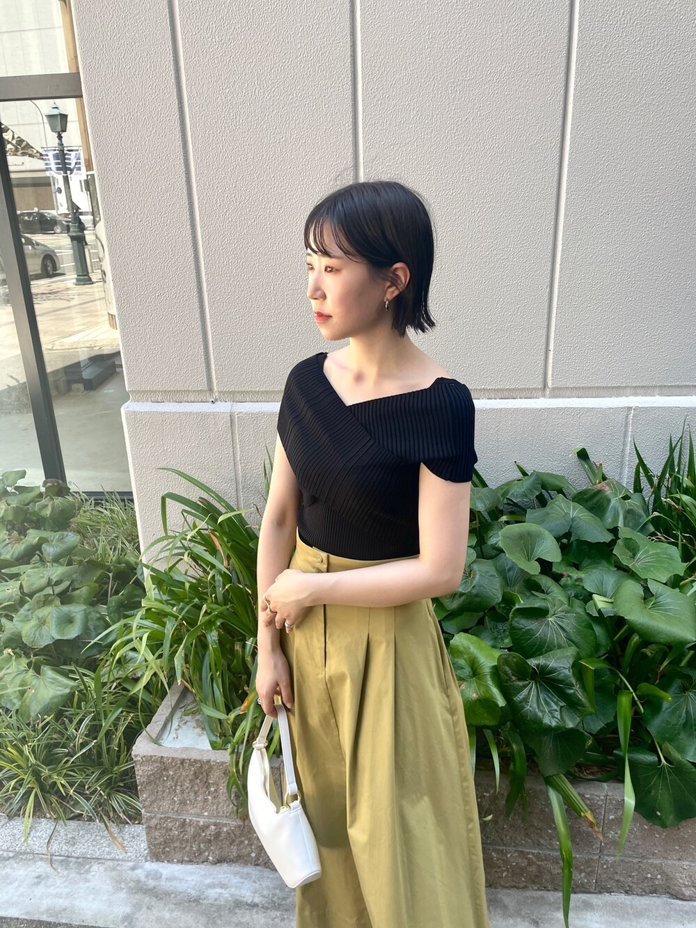 ブラック系のニット/セーター、イエロー系のスカート、ホワイト系のハンドバッグを着用したレディースの夏コーディネートの5枚目の写真