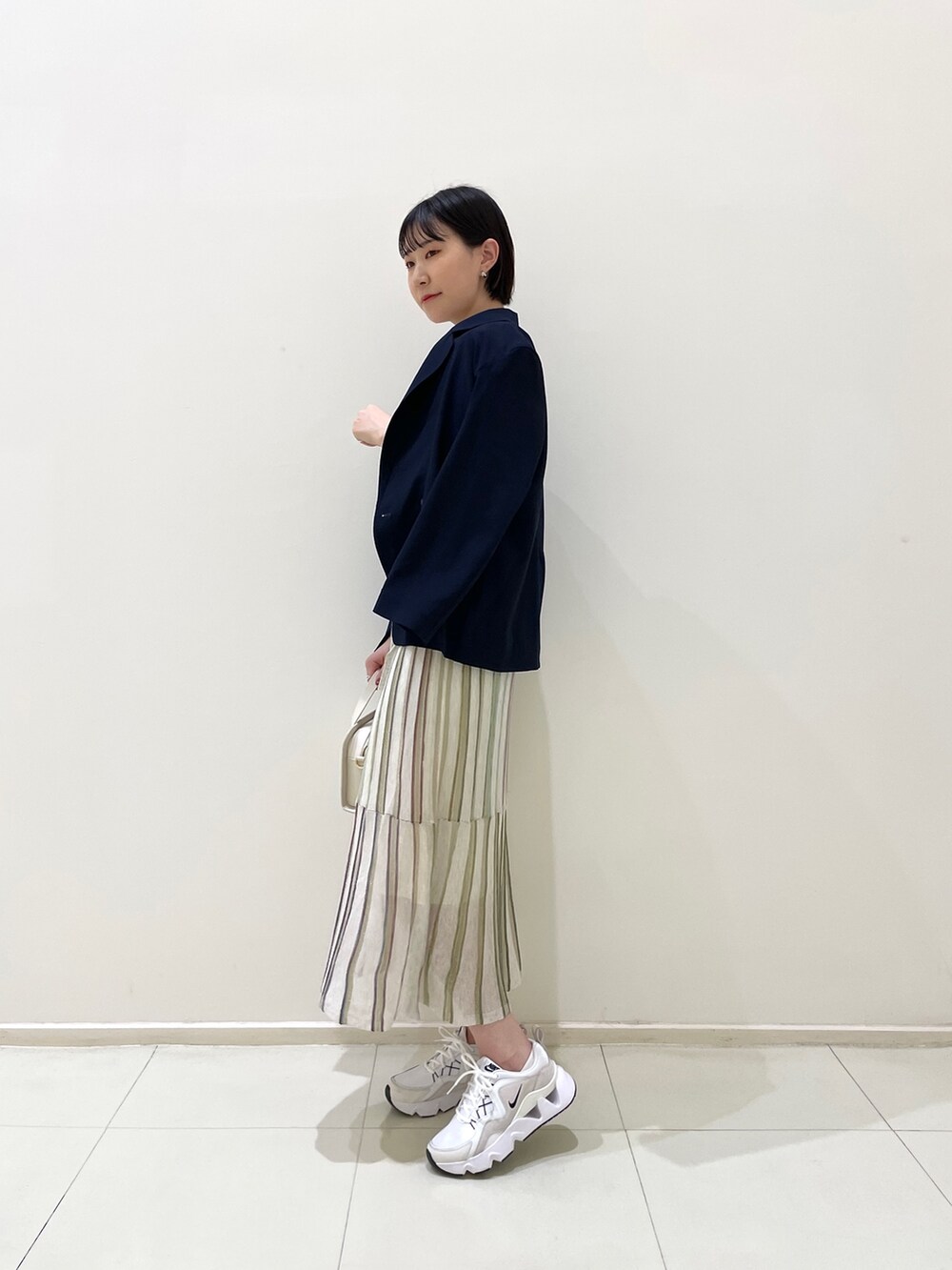 ブルー系のテーラードジャケット、ホワイト系のワンピース、ホワイト系のショルダーバッグを着用したレディースの春コーディネートの4枚目の写真