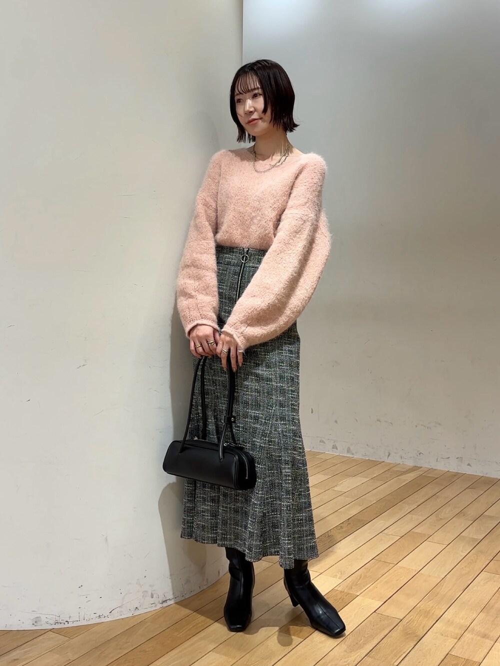 ブラック系のブーツ、ピンク系のニット/セーター、ブラック系のショルダーバッグを着用したレディースの冬コーディネートの2枚目の写真