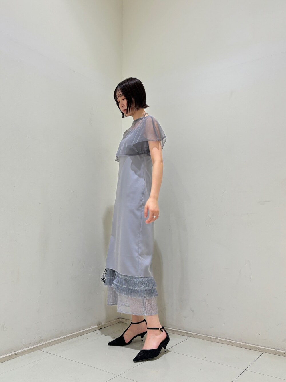 シルバー系のハンドバッグ、ブラック系のパンプス、パープル系のドレスを着用したレディースの夏コーディネートの2枚目の写真