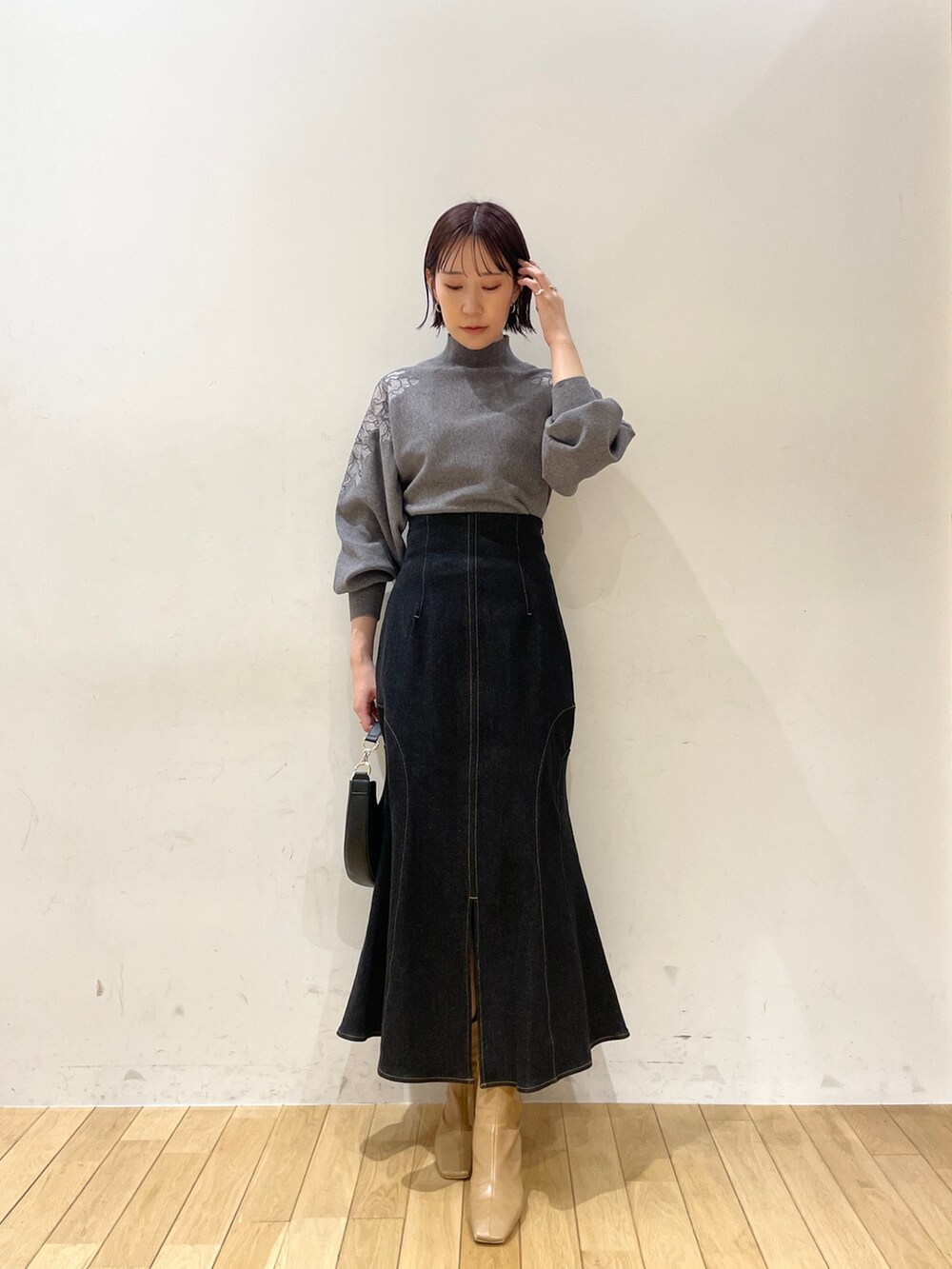 ベージュ系のブーツ、ブラック系のデニムスカート、ブラック系のハンドバッグを着用したレディースの夏コーディネートの2枚目の写真