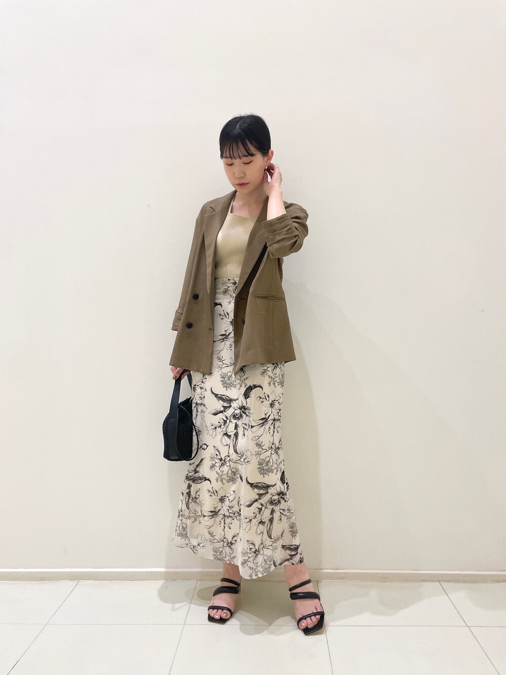 ブラウン系のテーラードジャケット、ベージュ系のニット/セーター、ホワイト系のスカートを着用したレディースの春コーディネートの3枚目の写真