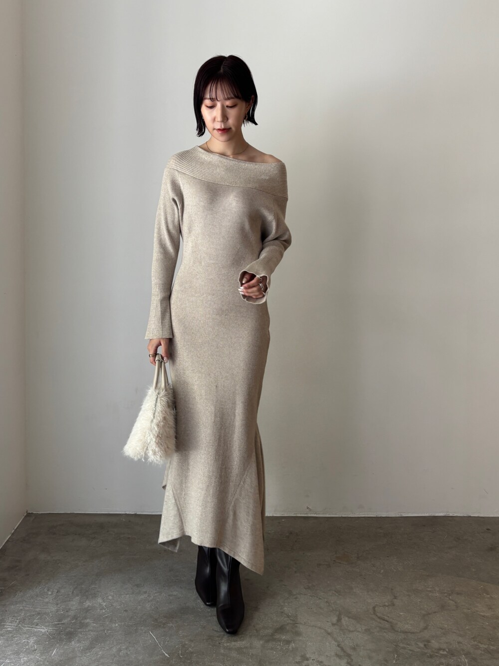 ベージュ系のワンピース、ホワイト系のボストンバッグ、ブラウン系のブーツを着用したレディースの秋コーディネートの2枚目の写真