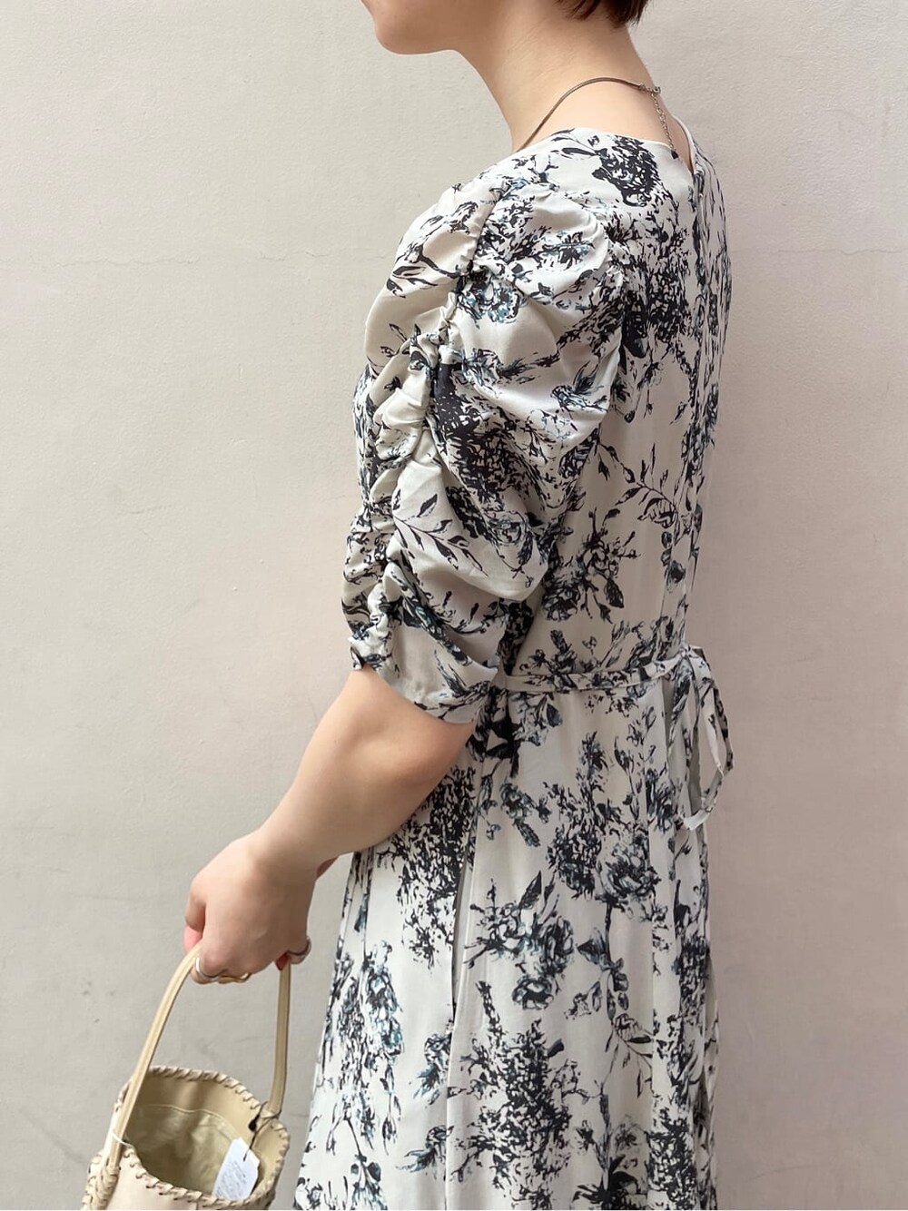 グレー系のワンピース、ブラック系のサンダル、ホワイト系のショルダーバッグを着用したレディースの春コーディネートの6枚目の写真