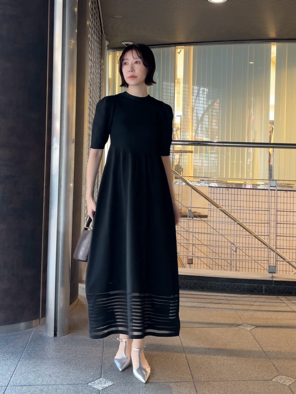 ブラウン系のハンドバッグ、シルバー系のパンプス、ブラック系のワンピースを着用したレディースの冬コーディネートの3枚目の写真