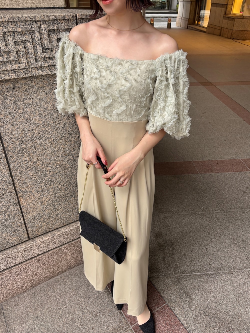 グリーン系のパンツドレス、ブラック系のパンプス、ブラック系のハンドバッグを着用したレディースの冬コーディネートの6枚目の写真