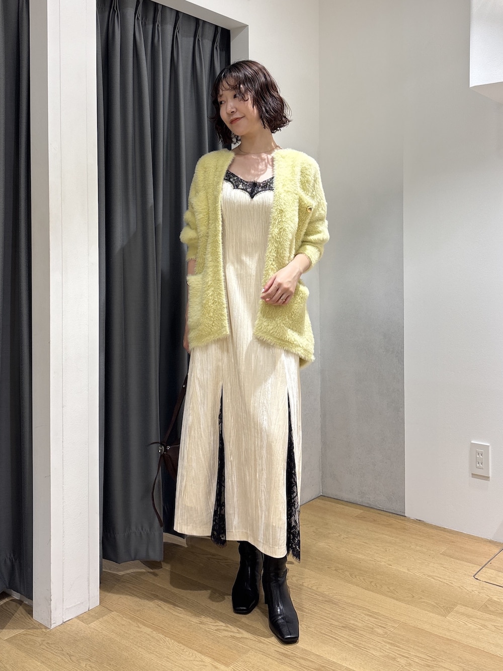 ホワイト系のワンピース、イエロー系のカーディガン/ボレロ、ブラウン系のハンドバッグを着用したレディースの秋コーディネートの2枚目の写真