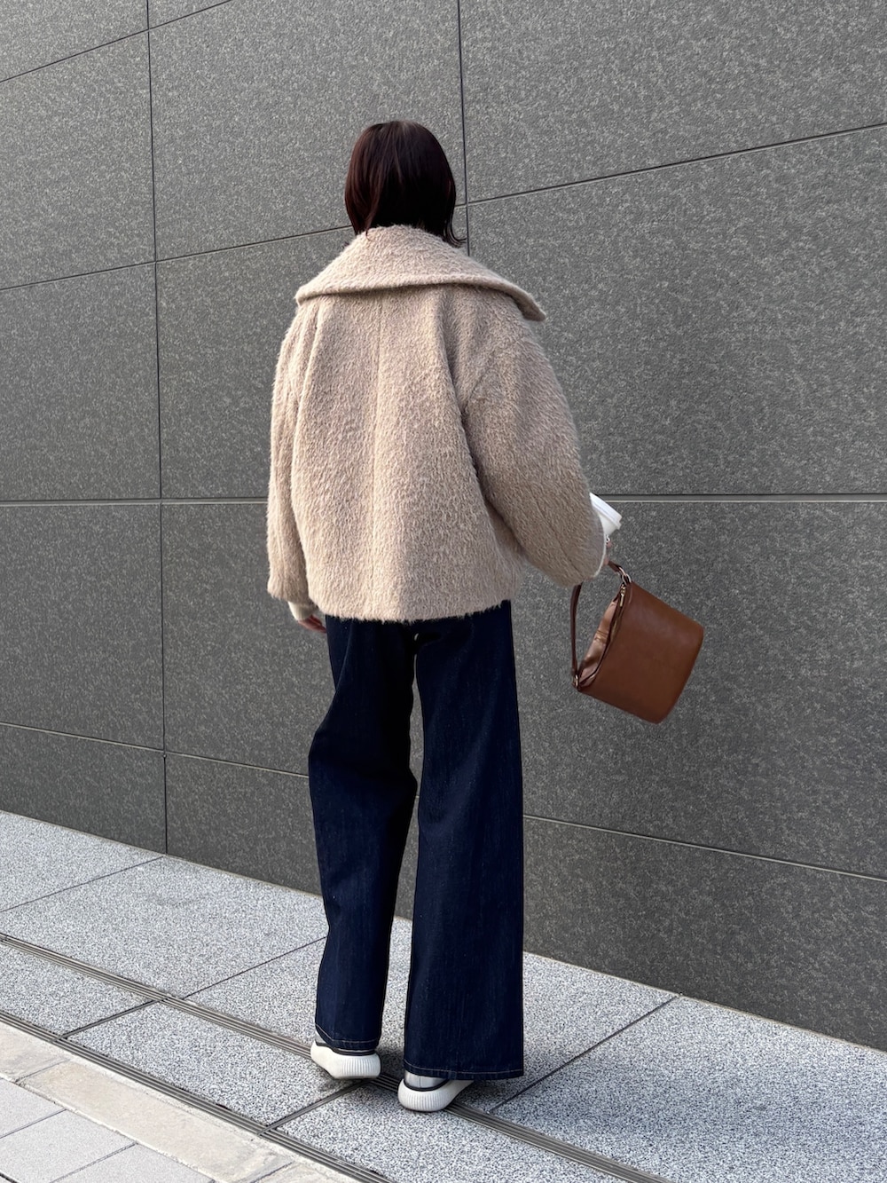 ブルー系のデニムパンツ、ベージュ系のその他アウター、ホワイト系のニット/セーターを着用したレディースの冬コーディネートの3枚目の写真