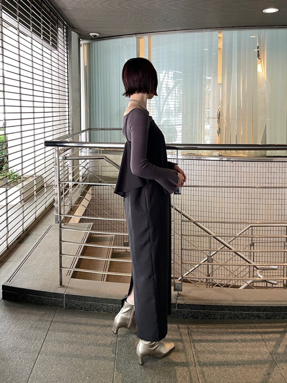 グレー系のニット/セーター、シルバー系のブーツ、ブラック系のワンピースを着用したレディースの秋コーディネートの3枚目の写真