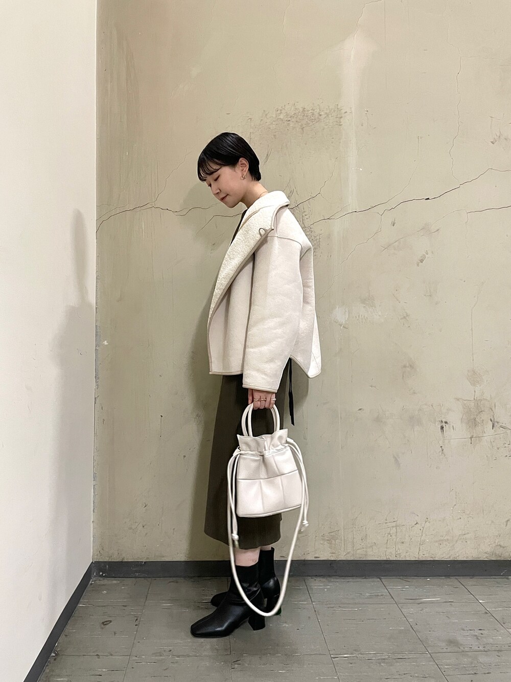 ホワイト系のブルゾン、ブラック系のブーツ、ブラウン系のワンピースを着用したレディースの秋コーディネートの8枚目の写真