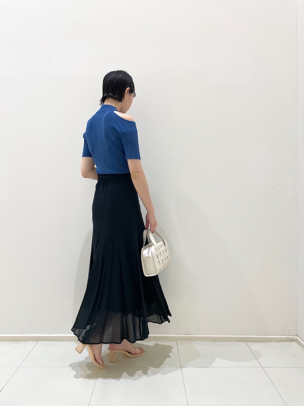 ブラック系のスカート、ホワイト系のショルダーバッグ、その他のサンダルを着用したレディースの夏コーディネートの4枚目の写真