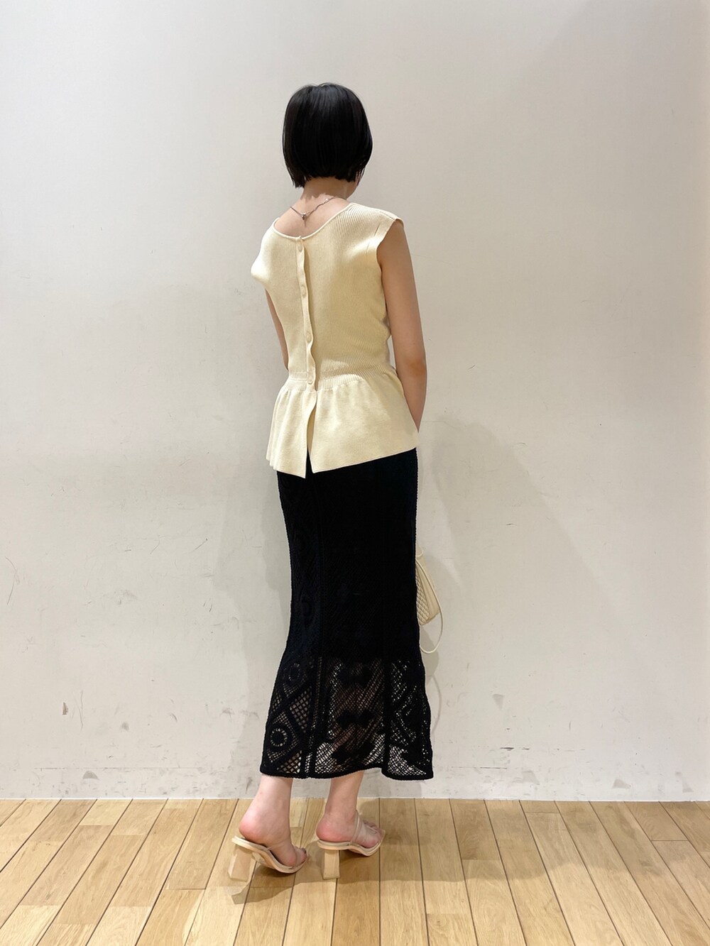 ベージュ系のハンドバッグ、ホワイト系のニット/セーター、ブラック系のスカートを着用したレディースの夏コーディネートの4枚目の写真