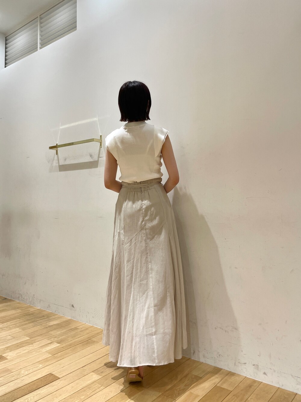 イエロー系のサンダル、グレー系のスカート、ホワイト系のニット/セーターを着用したレディースの夏コーディネートの5枚目の写真