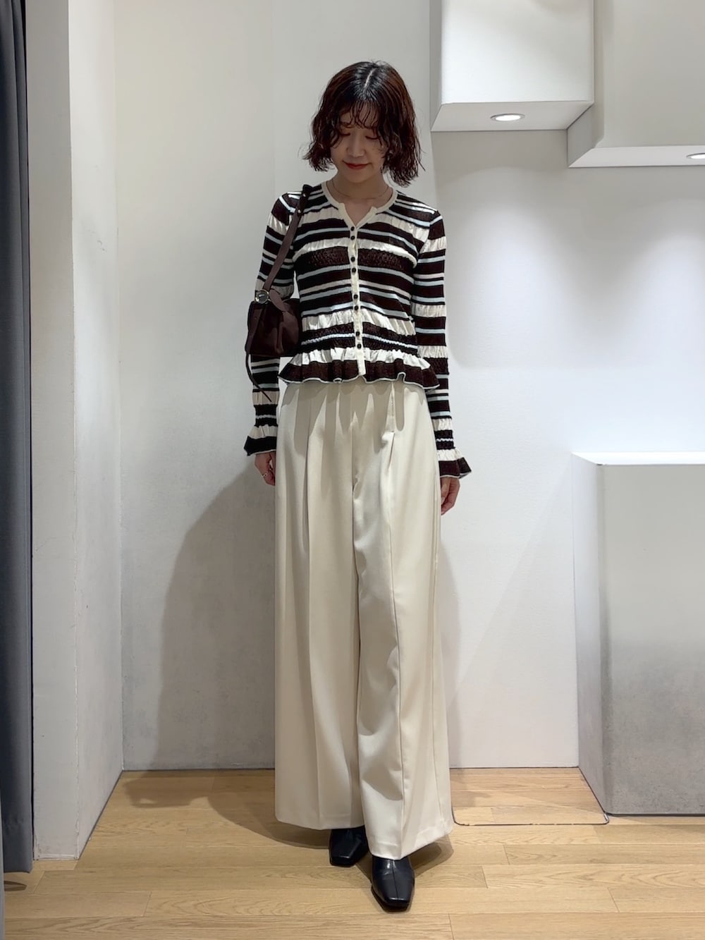ホワイト系のその他パンツ、ブラウン系のカーディガン/ボレロ、ブラック系のブーツを着用したレディースの秋コーディネートの2枚目の写真