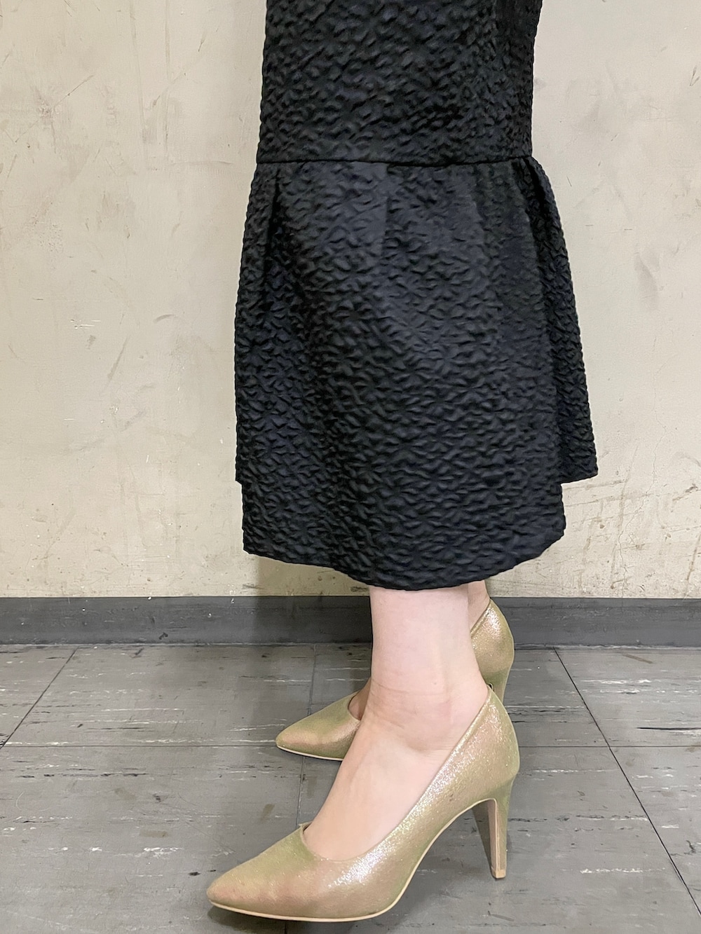 ブラック系のドレス、ゴールド系のハンドバッグ、ゴールド系のパンプスを着用したレディースの秋コーディネートの10枚目の写真