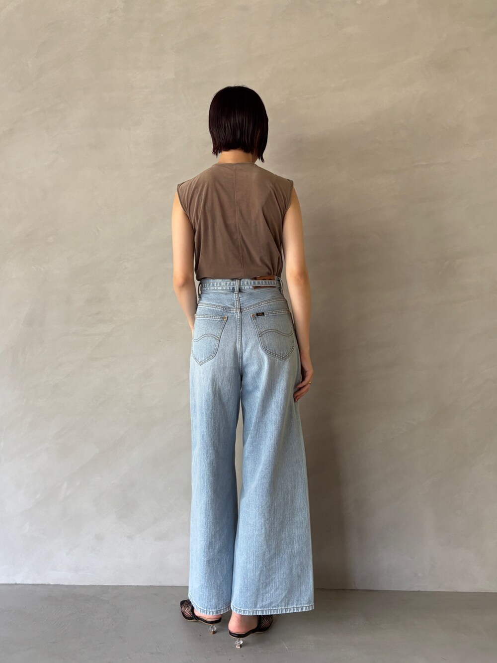 ブルー系のデニムパンツ、ブラック系のサンダル、ブラウン系のTシャツ/カットソーを着用したレディースの夏コーディネートの3枚目の写真