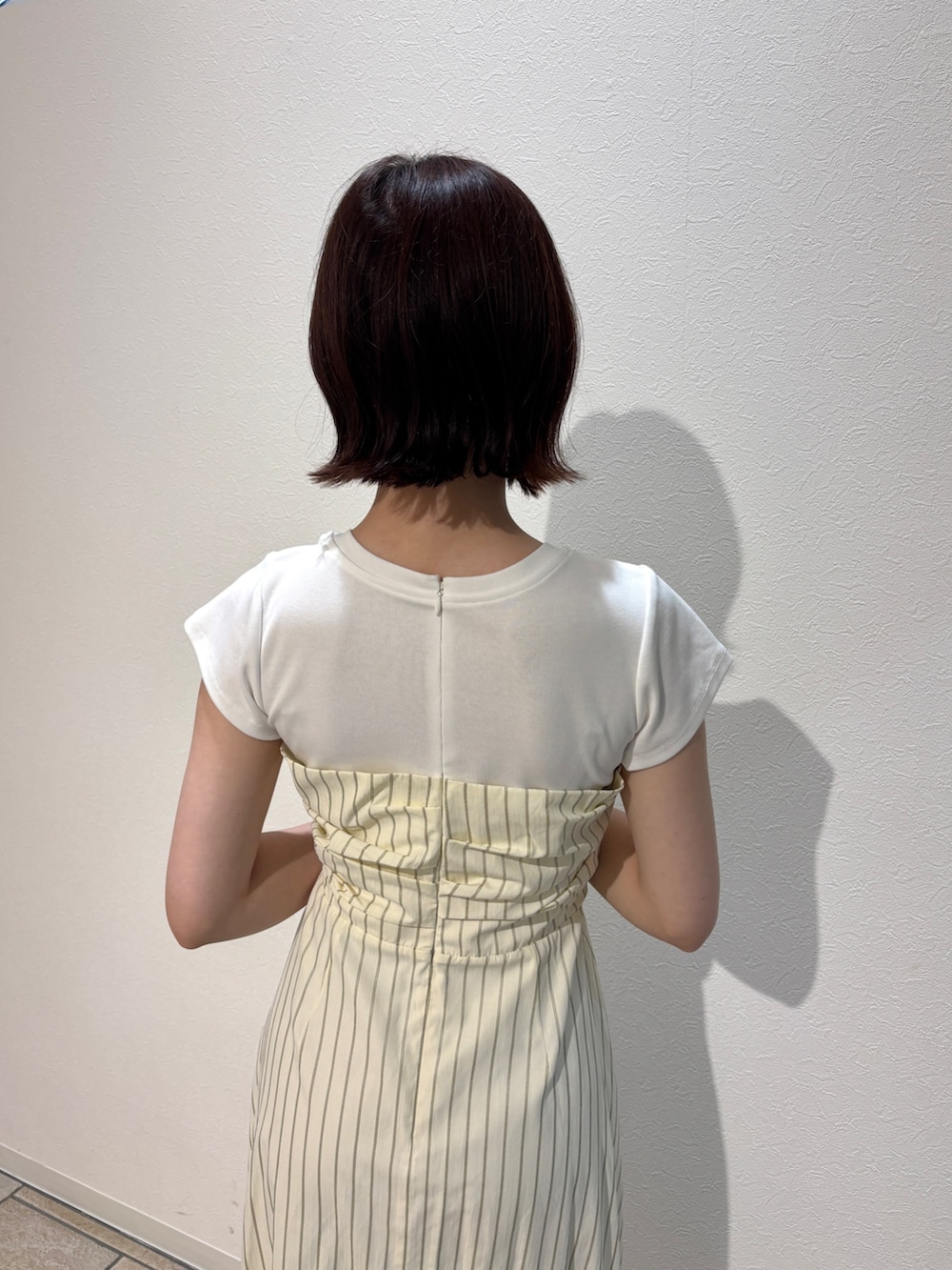 イエロー系のワンピース、ホワイト系のサンダル、ブラウン系のハンドバッグを着用したレディースの夏コーディネートの5枚目の写真