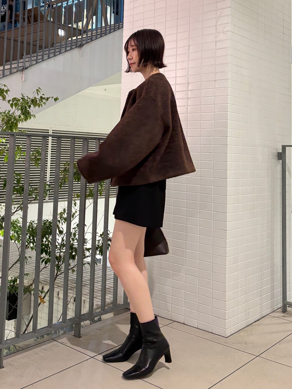 グレー系のニット/セーター、ブラウン系のブルゾン、ブラウン系のボストンバッグを着用したレディースの秋コーディネートの2枚目の写真