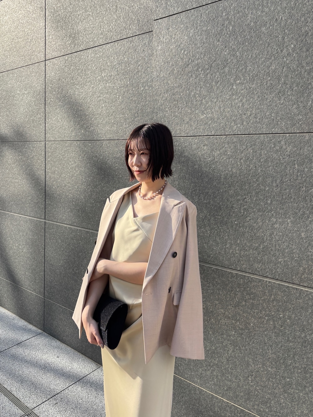 イエロー系のドレス、ブラック系のハンドバッグ、ブラック系のパンプスを着用したレディースの冬コーディネートの9枚目の写真