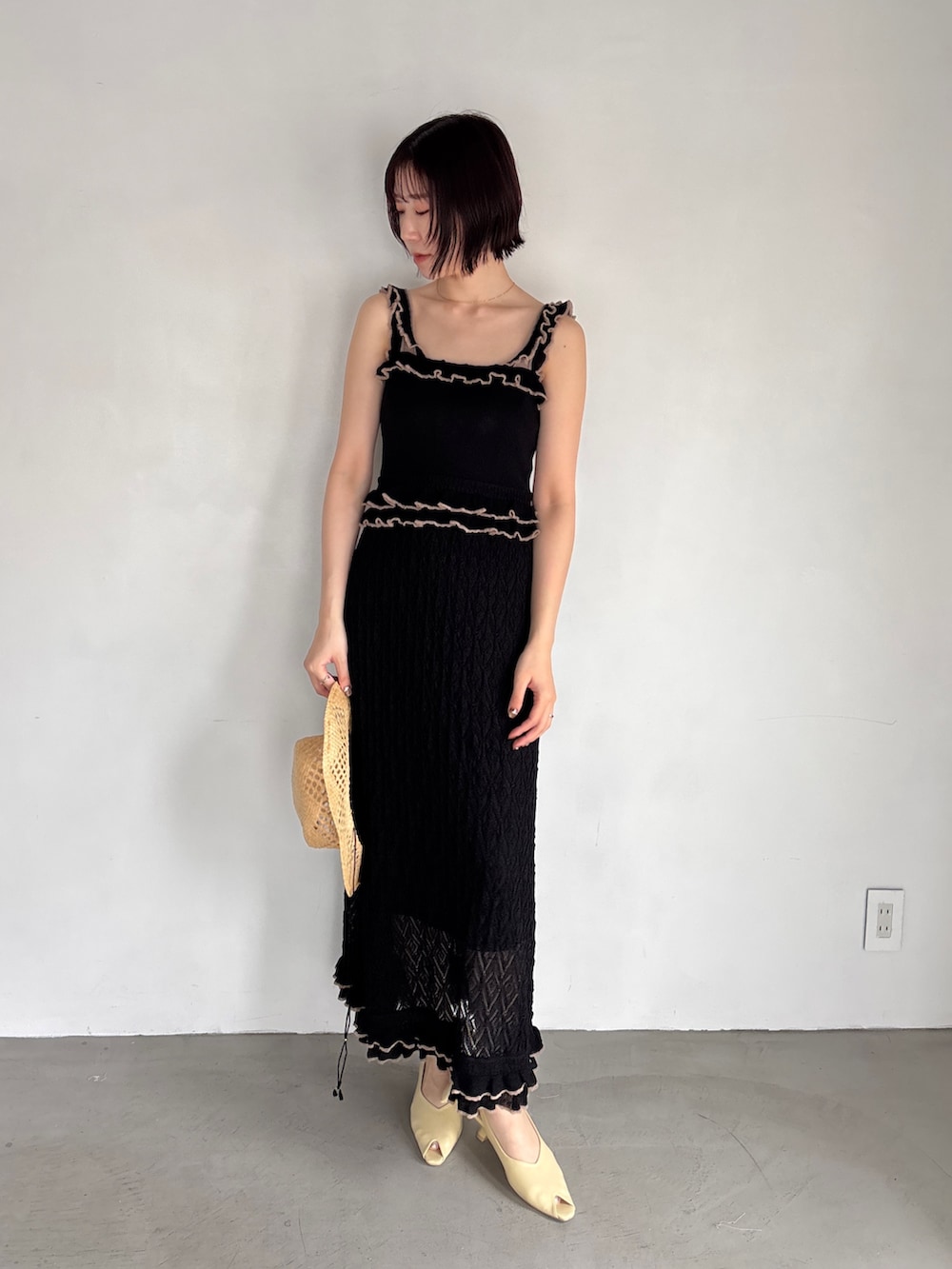 ブラック系のワンピース、イエロー系のパンプスを着用したレディースの夏コーディネートの2枚目の写真