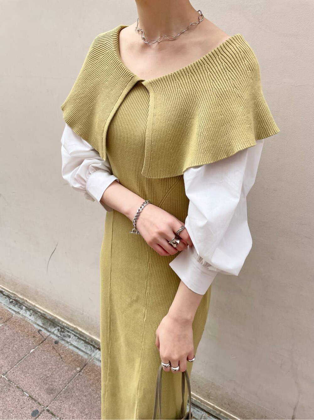 ベージュ系のハンドバッグ、ベージュ系のトレンチコート、イエロー系のワンピースを着用したレディースの冬コーディネートの4枚目の写真