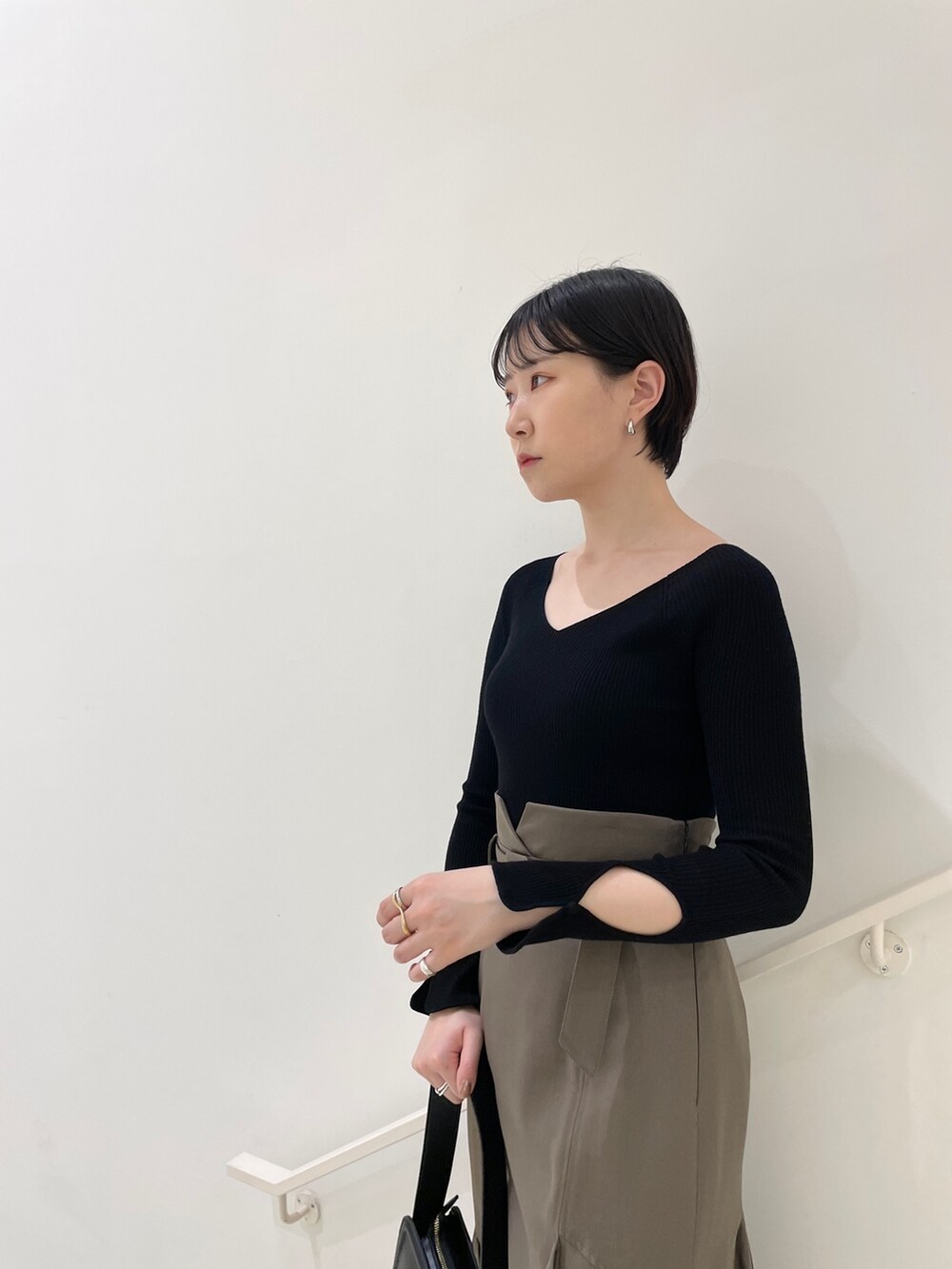 ブラウン系のスカート、ブラック系のニット/セーター、ベージュ系のサンダルを着用したレディースの春コーディネートの7枚目の写真