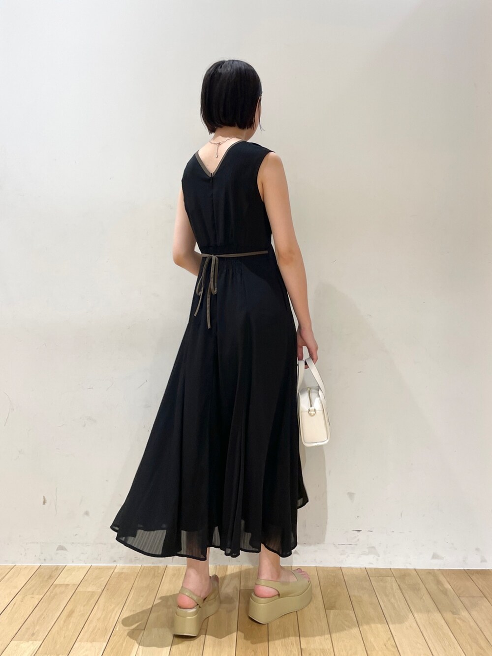 ホワイト系のショルダーバッグ、ベージュ系のサンダル、ブラック系のワンピースを着用したレディースの夏コーディネートの4枚目の写真