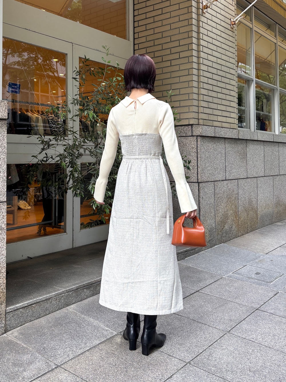 ホワイト系のワンピース、ブラウン系のハンドバッグ、ブラック系のブーツを着用したレディースの秋コーディネートの4枚目の写真