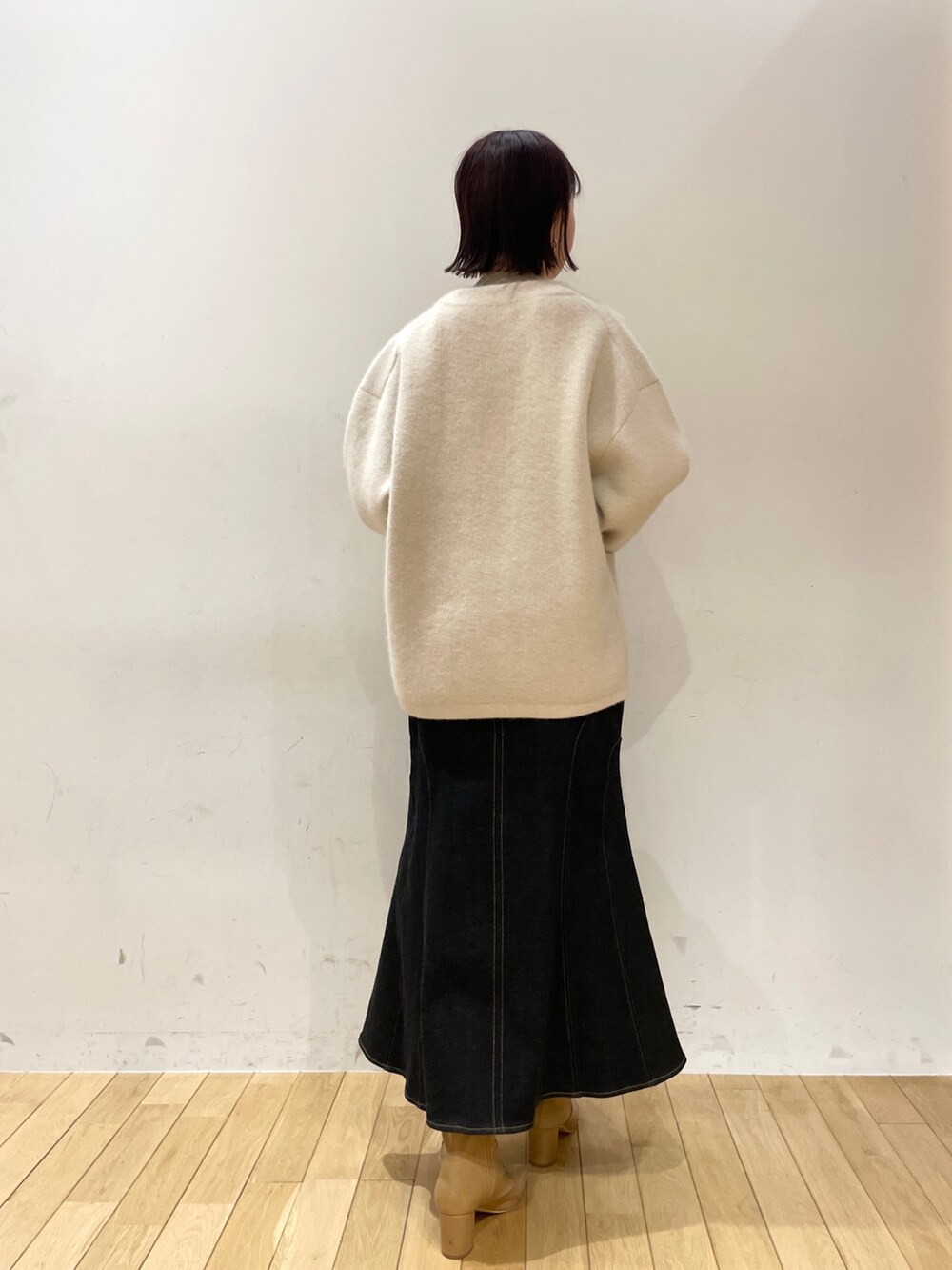 ブラック系のデニムスカート、ホワイト系のカーディガン/ボレロ、ベージュ系のニット/セーターを着用したレディースの秋コーディネートの4枚目の写真