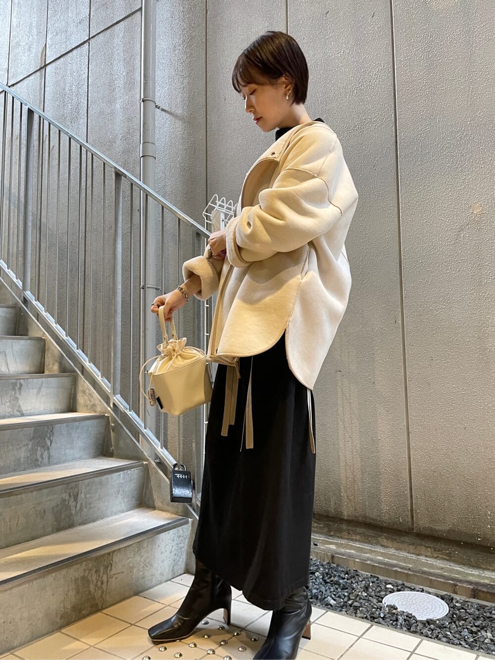 ブラック系のその他シューズ、ホワイト系のハンドバッグ、ブラック系のワンピースを着用したレディースの冬コーディネートの7枚目の写真