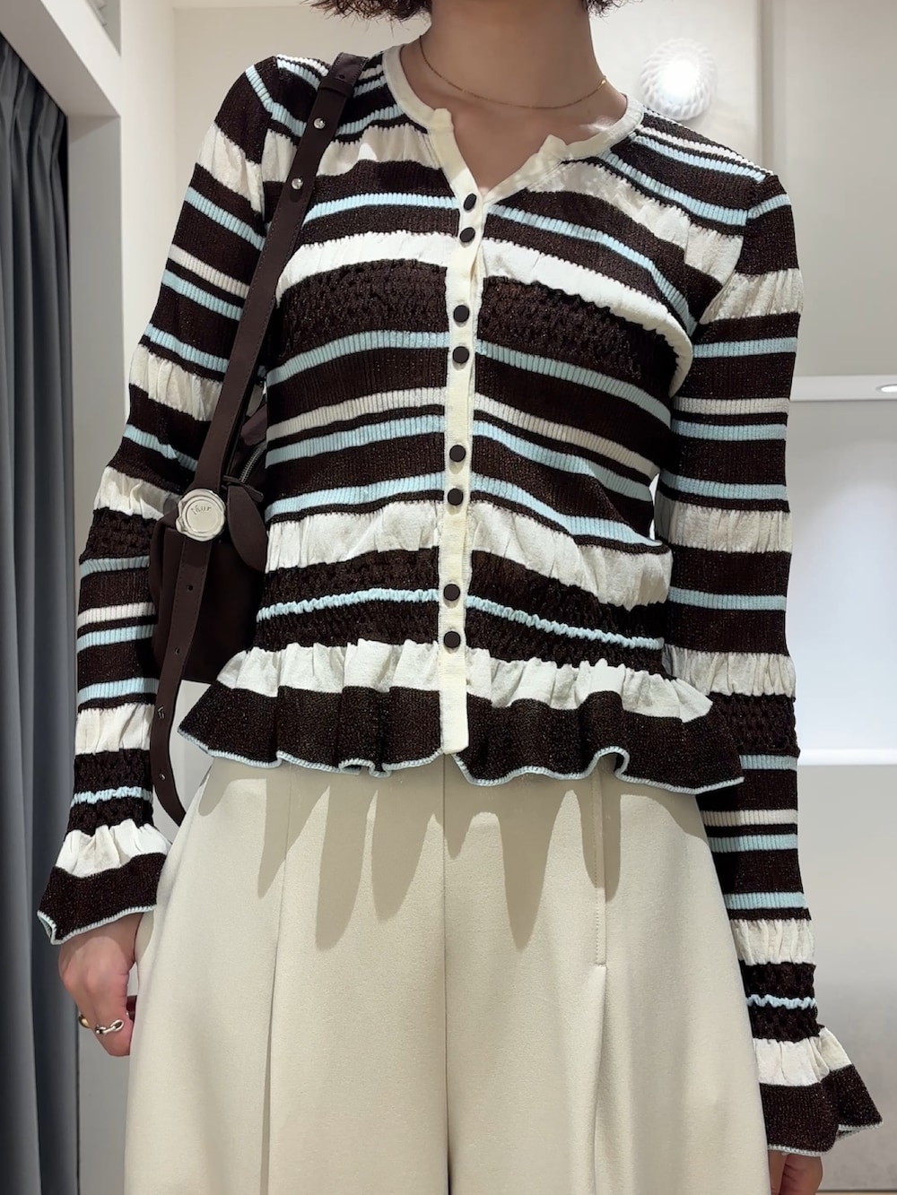 ホワイト系のその他パンツ、ブラウン系のカーディガン/ボレロ、ブラック系のブーツを着用したレディースの秋コーディネートの5枚目の写真