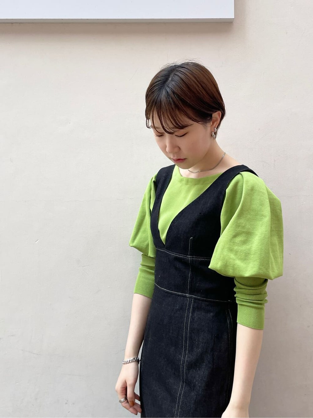 ブラック系のワンピース、グリーン系のニット/セーター、ブラック系のサンダルを着用したレディースの春コーディネートの6枚目の写真