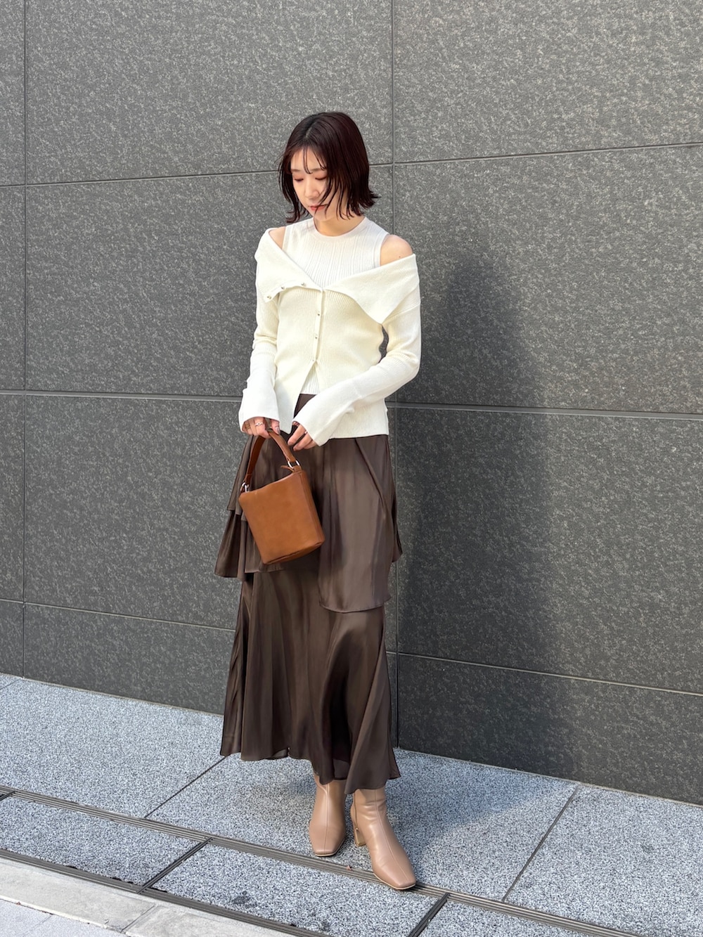 ホワイト系のムートンコート、ホワイト系のアンサンブル、イエロー系のハンドバッグを着用したレディースの冬コーディネートの8枚目の写真