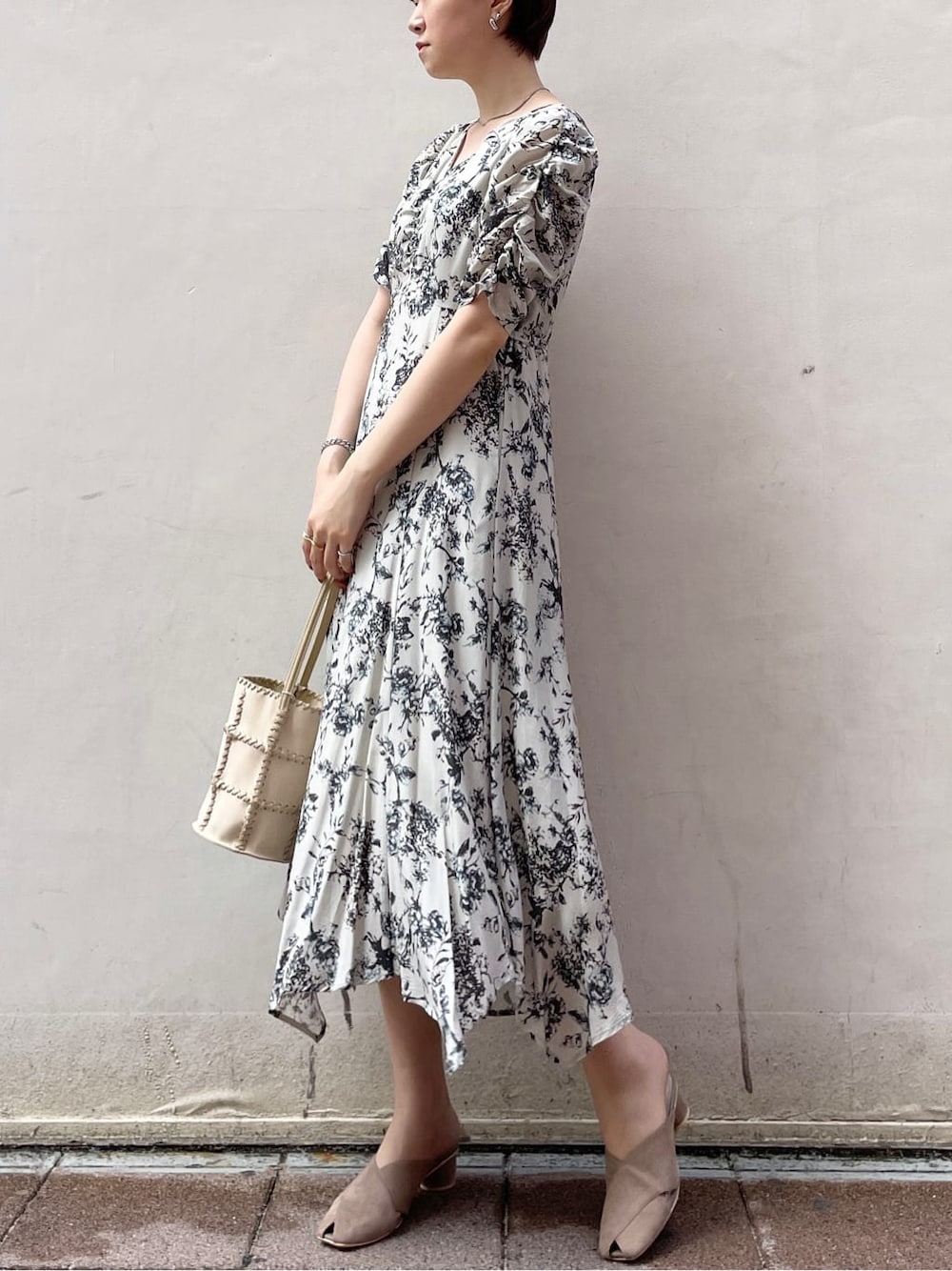 グレー系のワンピース、ブラック系のサンダル、ホワイト系のショルダーバッグを着用したレディースの春コーディネートの3枚目の写真