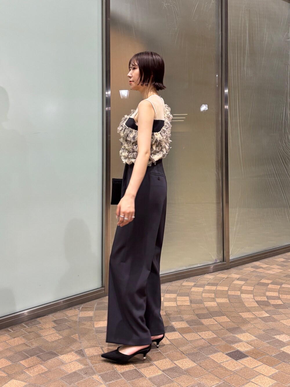 グレー系のパンツドレス、ブラック系のクラッチバッグ、ブラック系のパンプスを着用したレディースの夏コーディネートの4枚目の写真