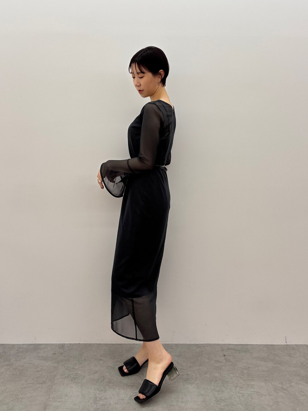 グレー系のワンピース、ブラック系のサンダル、ブラック系のベルトを着用したレディースの春コーディネートの2枚目の写真