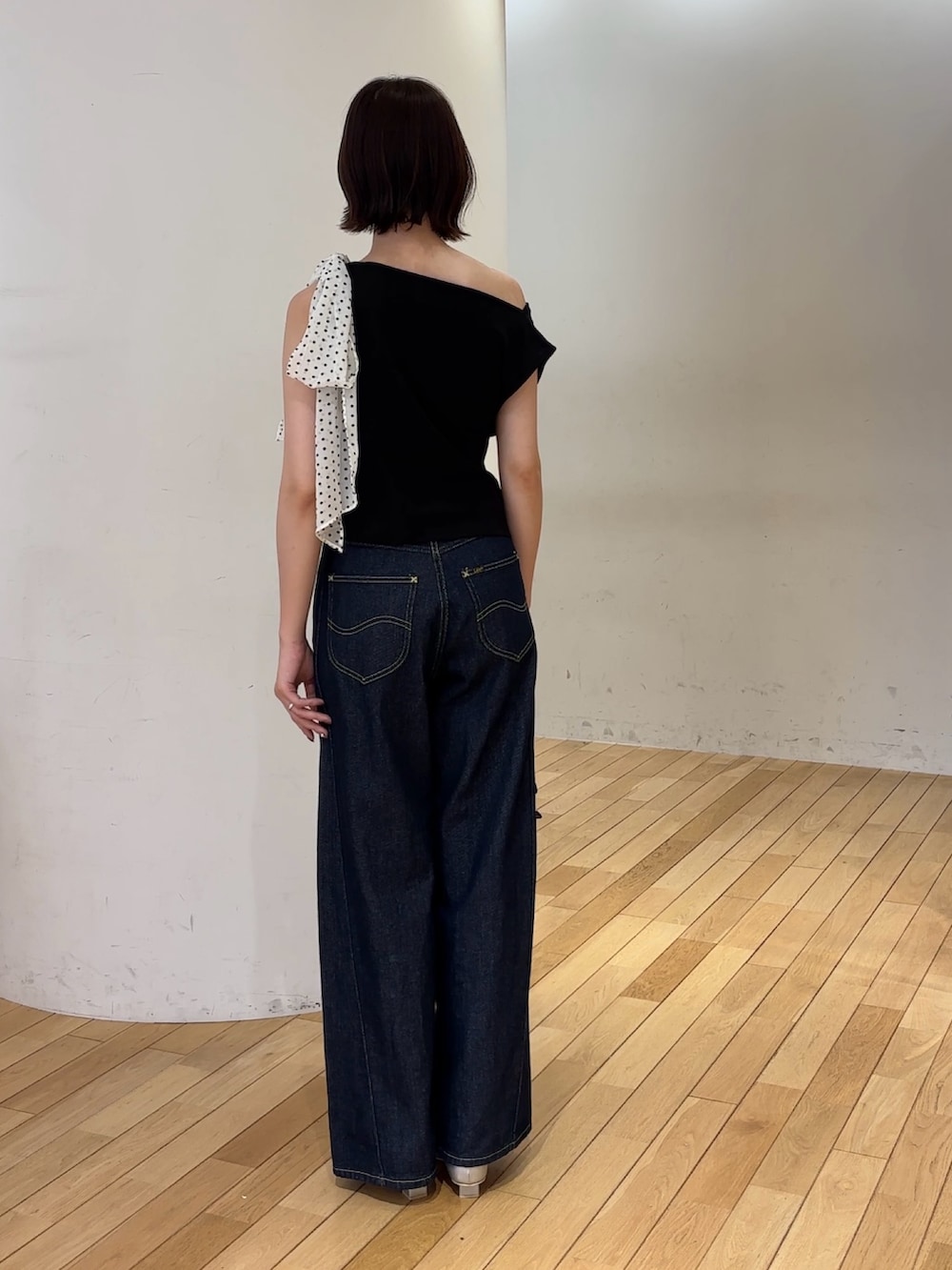 ブルー系のデニムパンツ、ブラック系のハンドバッグ、シルバー系のパンプスを着用したレディースの夏コーディネートの3枚目の写真