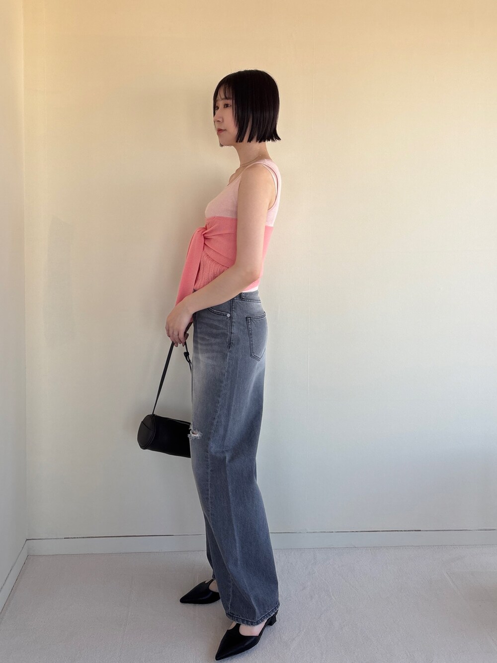グレー系のデニムパンツ、ピンク系のニット/セーター、ブラック系のパンプスを着用したレディースの春コーディネートの2枚目の写真