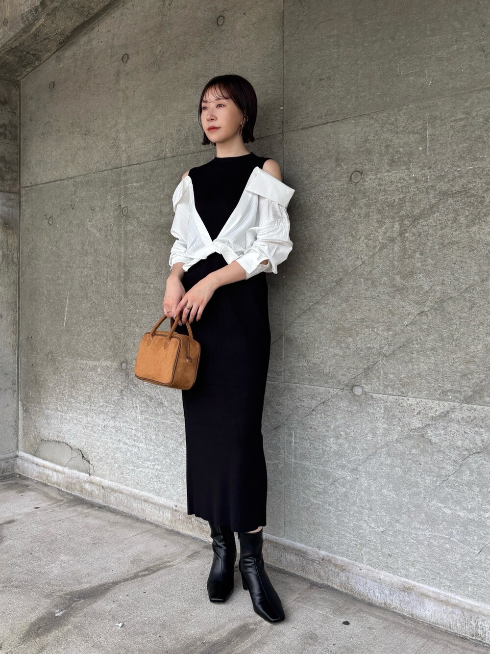 ブラック系のブーツ、イエロー系のハンドバッグ、ブラック系のワンピースを着用したレディースの秋コーディネートの2枚目の写真